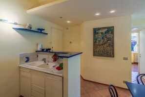 A kitchen with a sink, cabinets, and a painting on the wall.