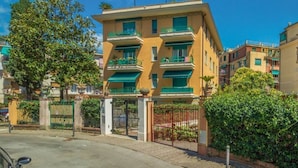 Un immeuble résidentiel à plusieurs étages, doté de balcons, d’une entrée sécurisée et d’une allée pavée.
