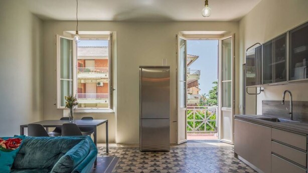 Cocina compacta con refrigerador, mesa de comedor y sofá.