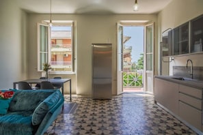 A compact kitchen with a refrigerator, dining table, and a sofa.
