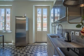 A kitchen with a stainless steel refrigerator, a sink, and a kettle.