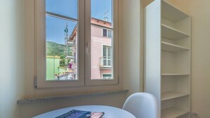 Una habitación con ventana, una mesa con revistas y una silla blanca.