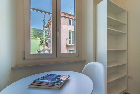 A room with a window, a table with magazines, and a white chair.