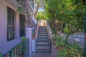 A staircase leading to a building entrance, surrounded by greenery and a metal gate. -  LA BOUGAINVILLE - Relaxation, Garden, and Parking (Santa Margherita Ligure)