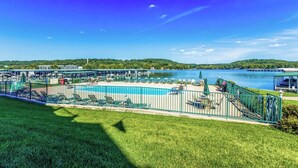 A pool area with lounge chairs and a view of a lake.