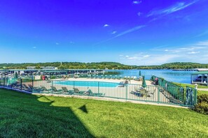 A pool area with lounge chairs and a view of a lake.