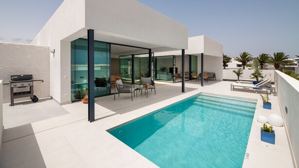 A modern house with a swimming pool, outdoor seating, and a barbecue area.