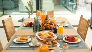 A breakfast table with various food items, including fruits, pastries, and beverages.