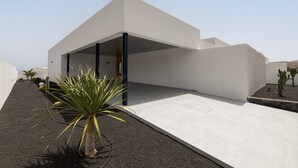 A modern building with a flat roof, a covered entrance, and a paved patio area.