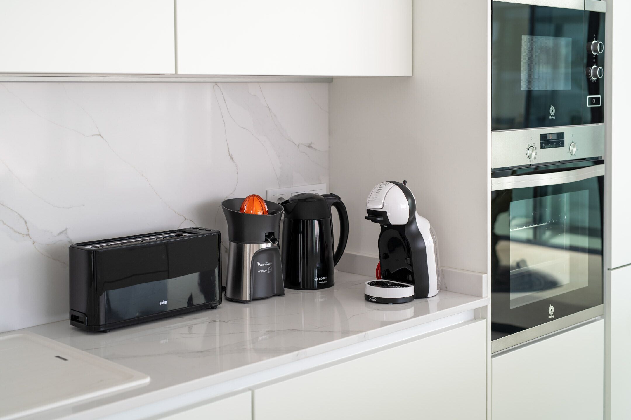 A modern kitchen with a toaster, coffee maker, and kettle on the counter.