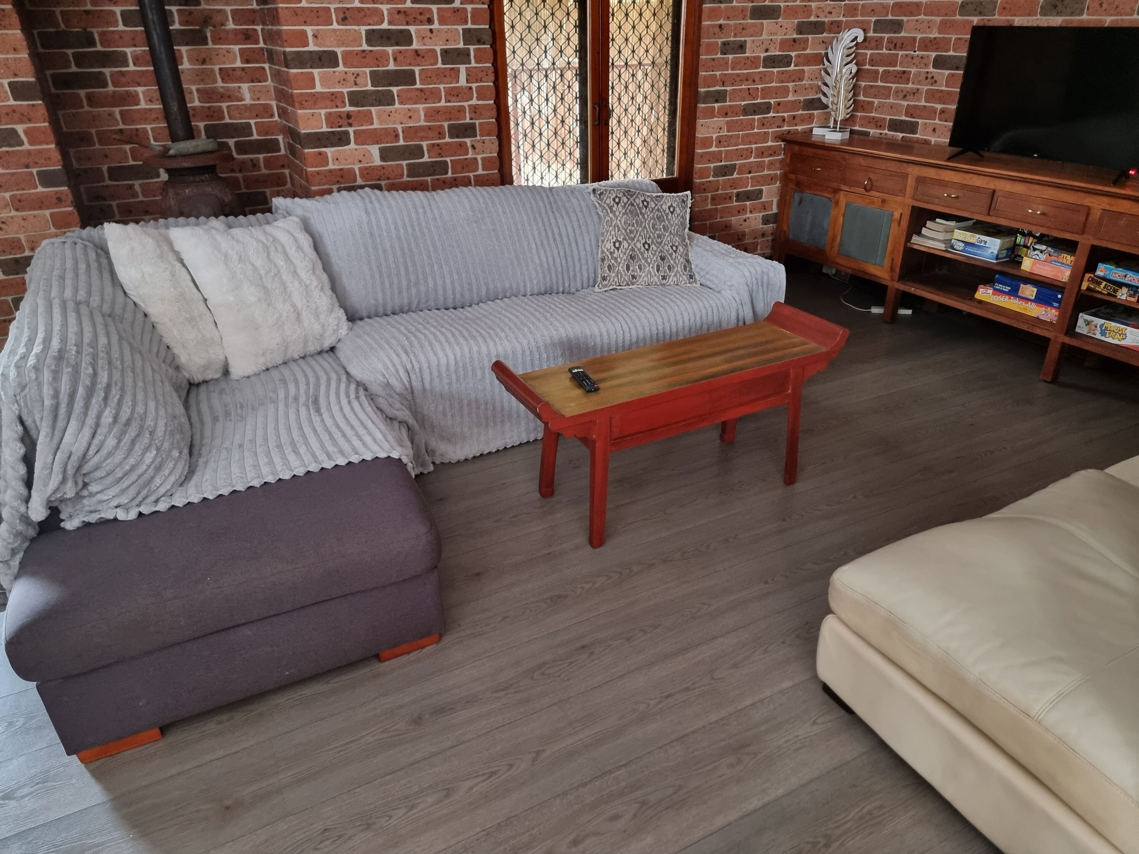 A living room with a sofa, ottoman, coffee table, TV stand, and bookshelves.