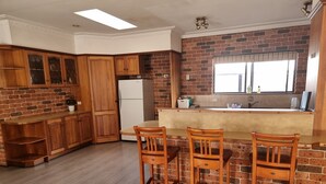 Una cocina con armarios de madera, un refrigerador, una pared de ladrillo y una ventana.