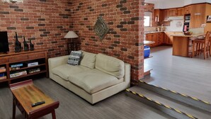 Un salón con pared de ladrillo, un sofá, una mesa de centro y un televisor.