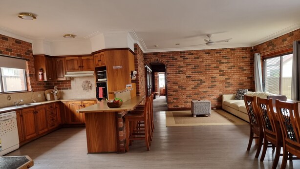 Cocina con alacenas de madera, una isla central y una pared de ladrillo.