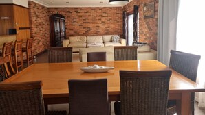 Un comedor con pared de ladrillo, muebles de madera y una lámpara colgante.