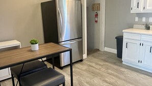 Una cocina moderna con un refrigerador de acero inoxidable, una mesa de comedor de madera con un banco y armarios blancos.