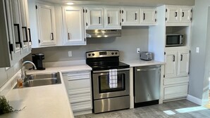 Una cocina moderna con armarios blancos, electrodomésticos de acero inoxidable y una isla central.