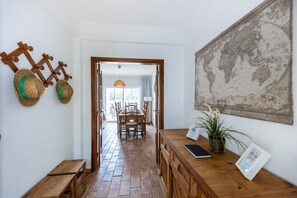 Ein Essbereich mit Holztischen, einem Backsteinboden, einer großen Weltkarte an der Wand und einer Pflanze auf dem Tisch.