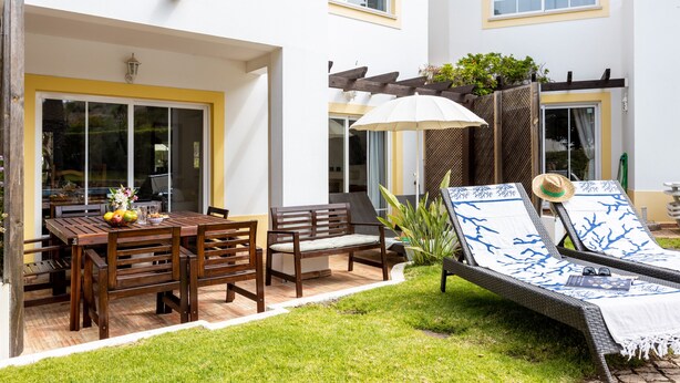 A patio with a dining table, chairs, a lounge chair, and a small garden area. - CoolHouses Algarve Luz | Casa Sirrah (Luz)