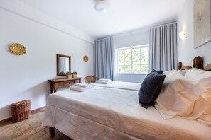 Une chambre à coucher avec un lit, une commode, un miroir et une fenêtre avec des rideaux.