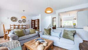A spacious living room with a dining area, a kitchen with a view, and a staircase leading to another level. - CoolHouses Algarve Luz | Casa Sirrah (Luz)