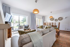 A spacious living area with a sofa, a dining table, and a television. - CoolHouses Algarve Luz | Casa Sirrah (Luz)