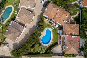 Vista aérea de una zona residencial con varias casas, dos piscinas y un césped bien cuidado.