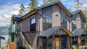 Une maison moderne à deux étages, dotée d’un balcon, d’un escalier et offrant une vue sur les montagnes.