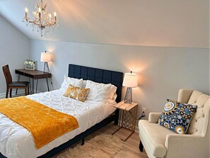 A bedroom with a bed, bedside tables, a desk, a chair, and a chandelier. - Spacious Coastal Carolina Home with Epic Game Room (Conway)