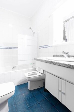 Bathroom features a white toilet, bidet, bathtub, and showerhead, along with a sink and mirror.