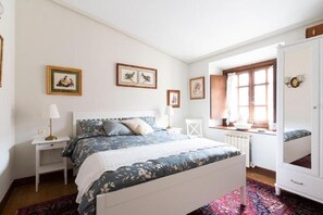 Cozy retreat with a large bed, nightstand, and dresser, featuring a floral-patterned duvet and framed artwork.