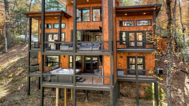 A multi-level wooden cabin with large windows, a hot tub, and a deck. - Modern 4BR Cabin w easy access, hot tub & a view! (Blue Ridge)