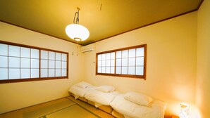 Ett traditionellt japanskt rum med tatamimattor på golvet, en futonmadrass, skjutbara shojidörrar och en taklampa.