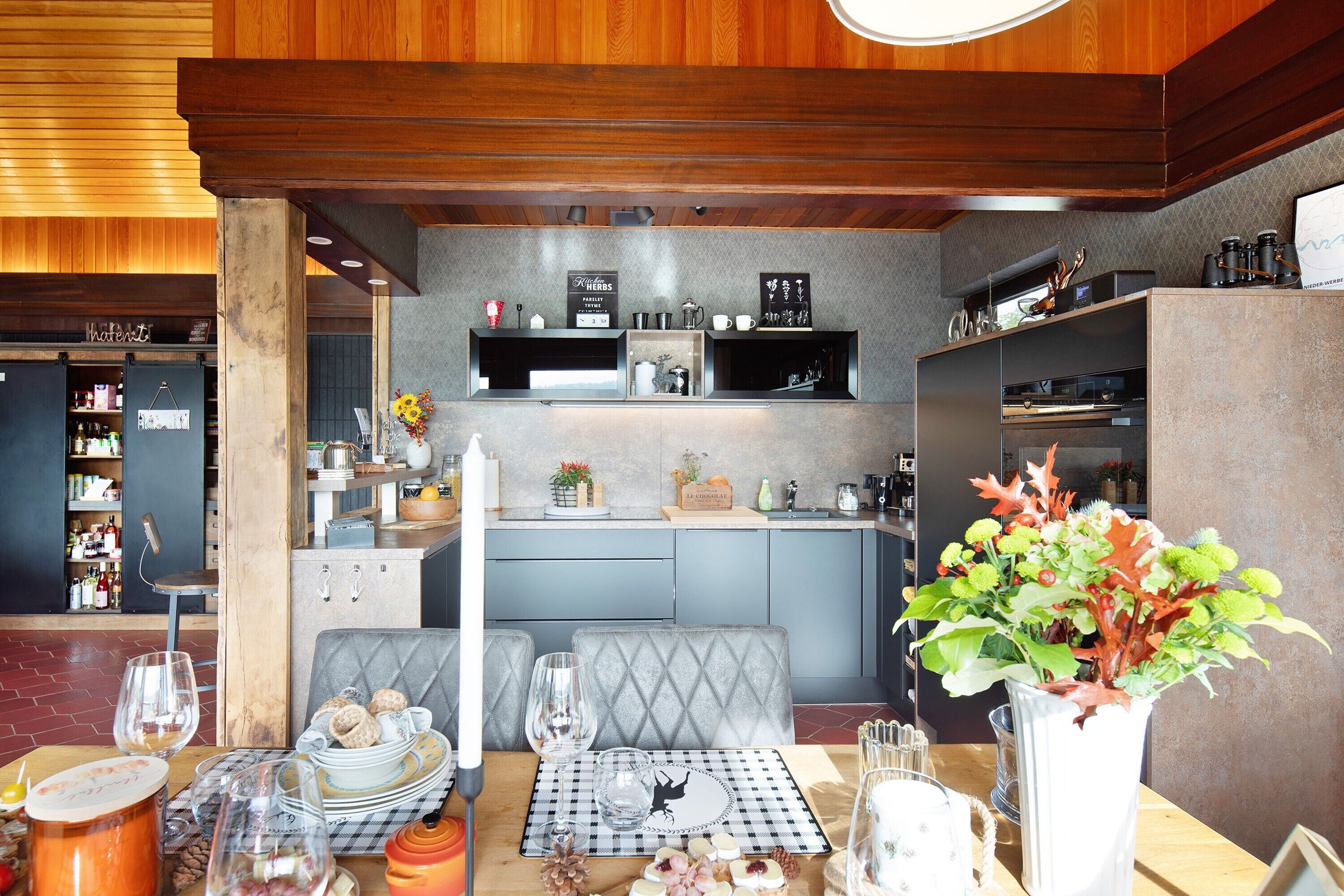A dining area with a checkered table mat, a vase with flowers, and a bar area in the background.