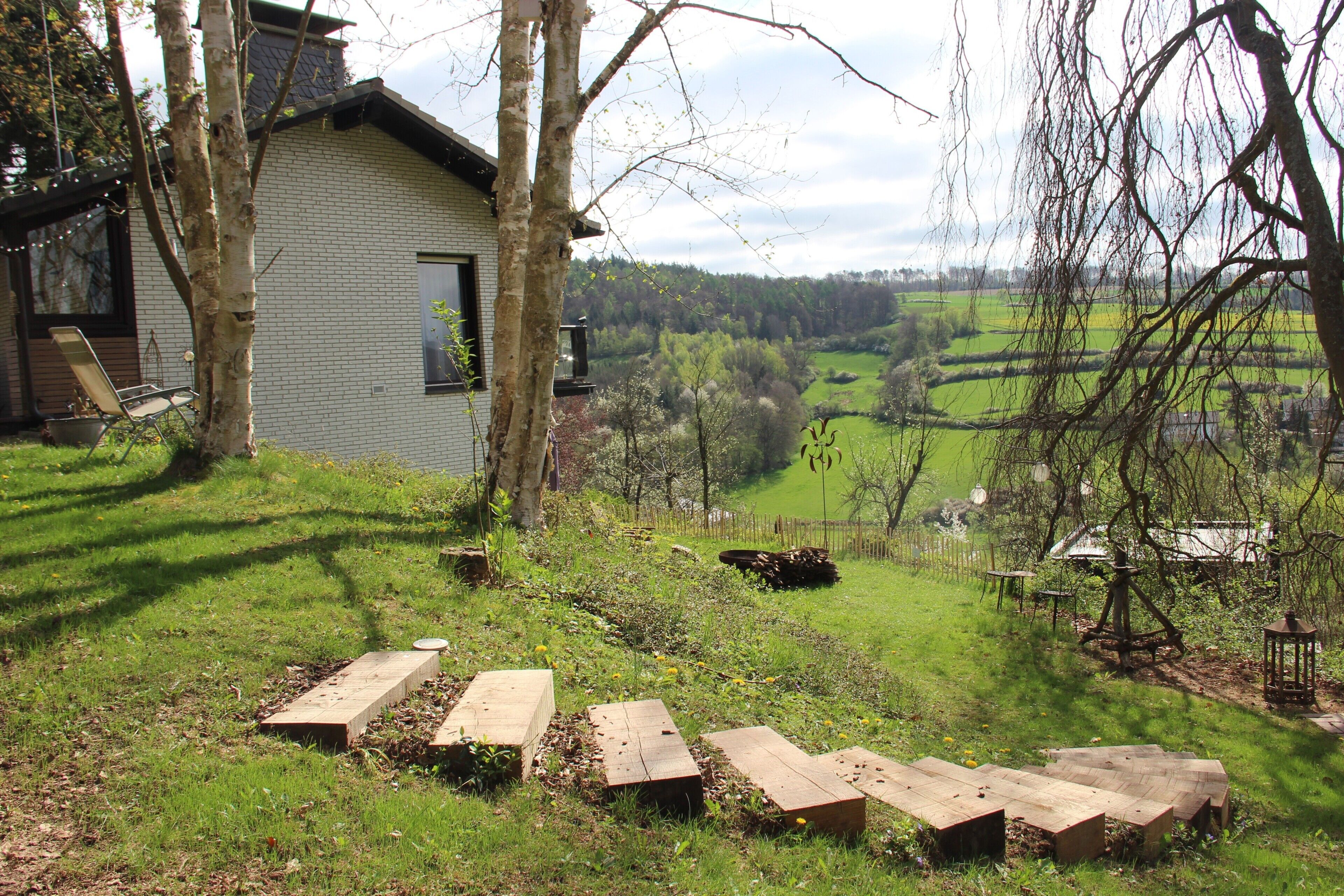 Een huis met een bakstenen gevel, een houten terras en uitzicht op een groen landschap.