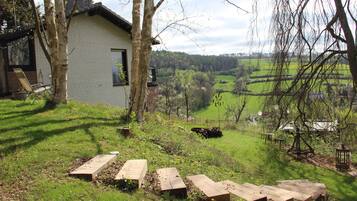 Een huis met een bakstenen gevel, een houten terras en uitzicht op een groen landschap.