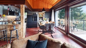 Une cuisine moderne avec un coin bar, un espace repas offrant une vue agréable et un coin salon confortable avec une grande fenêtre.