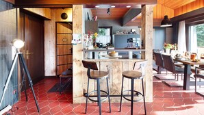Une cuisine moderne agrémentée d’éléments en bois, un coin bar avec des tabourets et une table à manger avec des chaises.