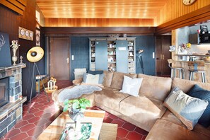 Una sala de estar acogedora con un sofá, una mesita de centro, una chimenea y una zona de cocina al fondo.