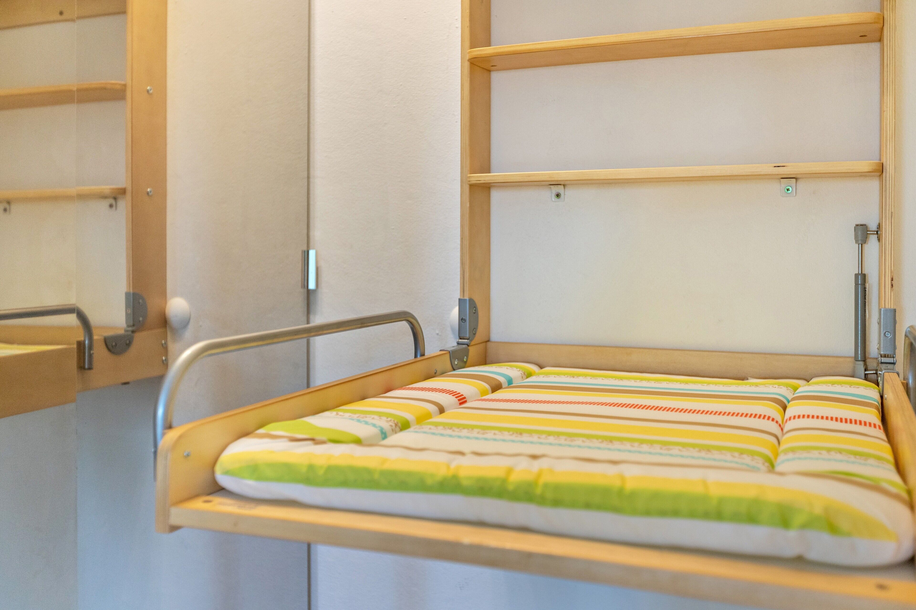 Una cama de hospital con colchón a rayas y barandillas de metal.