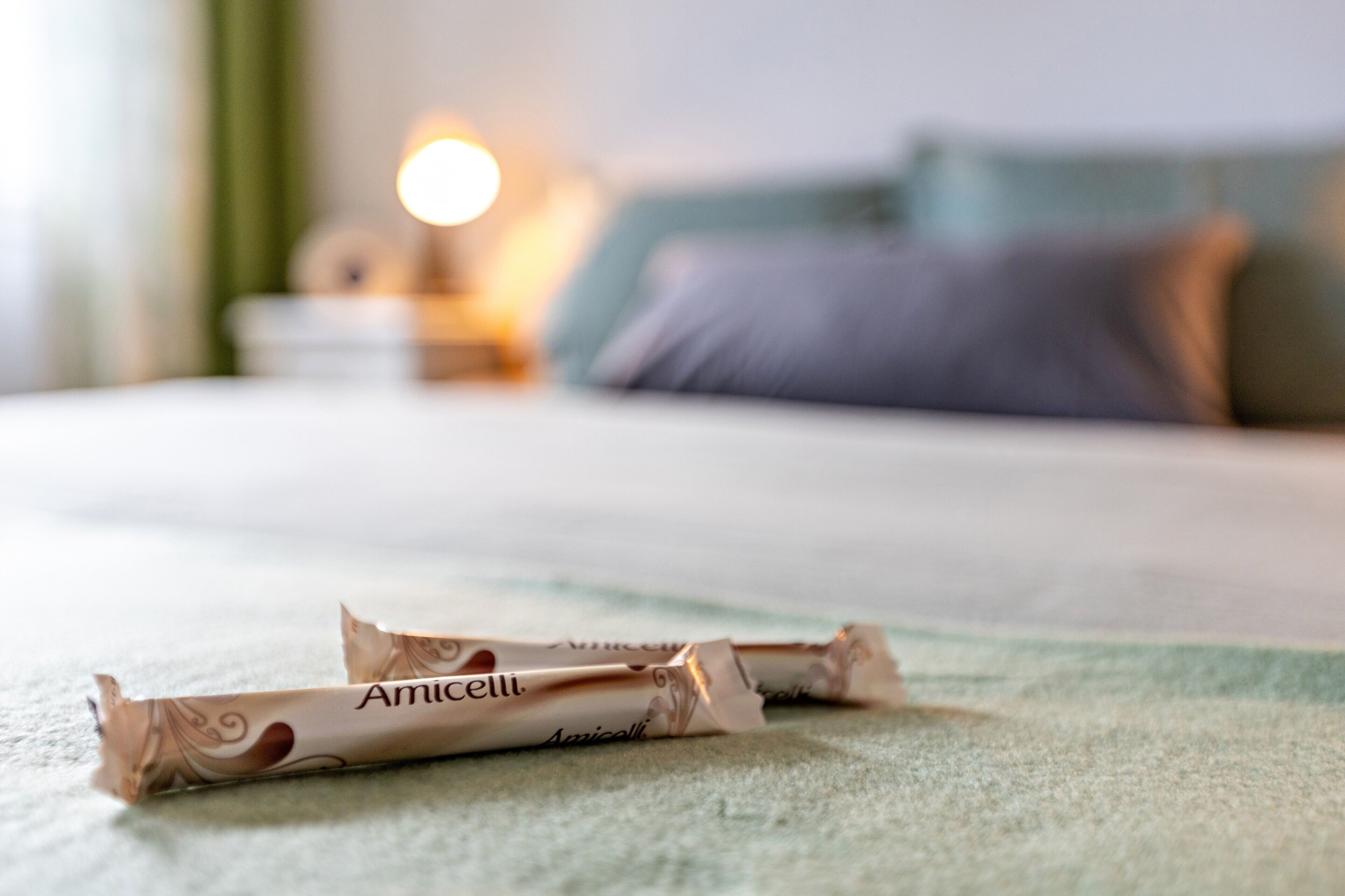 A bed with a pillow and a bedside table with a lamp.