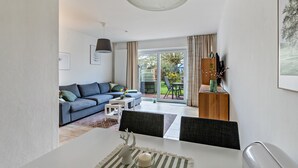 Un salon moderne comprenant un canapé, une table à manger, des chaises et donnant sur l’extérieur.
