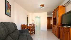 Ein Wohnzimmer mit grauem Sofa, Holzschrank und Fernseher.