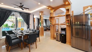 A modern kitchen with a stainless steel refrigerator, wooden cabinetry, and a dining area with a table set for six.