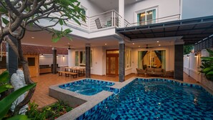 A modern house with a swimming pool, a dining area, and a balcony.