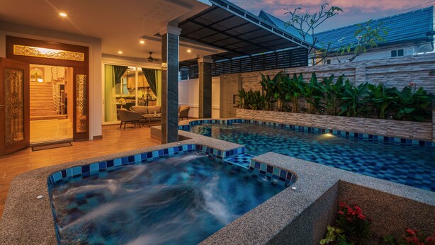 A modern house with a swimming pool, a covered patio, and a staircase leading to the upper floor.