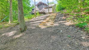 Eine Holztreppe führt zu einem von Bäumen umgebenen Haus.