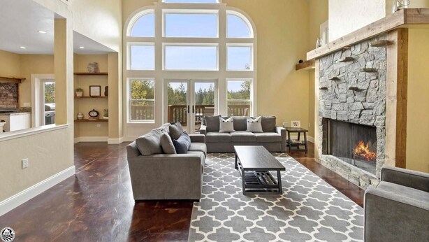 A spacious living room with a stone fireplace, large windows, and a cozy seating area.