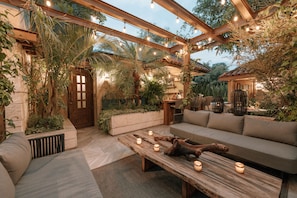 An outdoor patio with a wooden bench, cushions, and candles. - Casa Luciana Condesa (Mexico City)