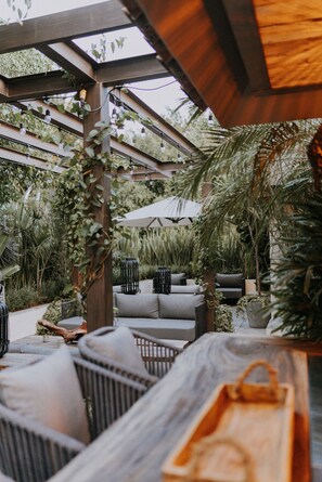 An outdoor patio with wicker furniture, a wooden table, and a pergola structure. - Casa Luciana Condesa (Mexico City)